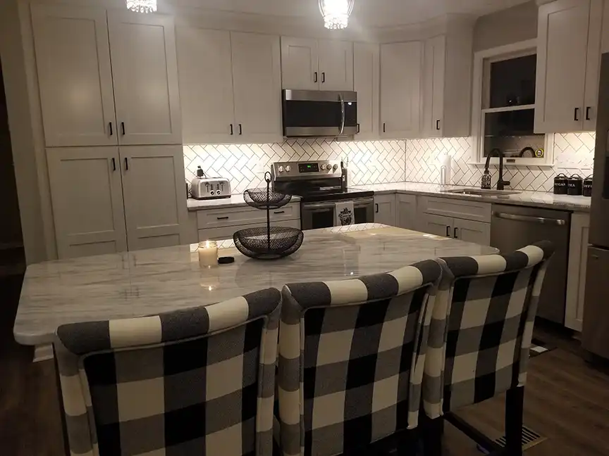 Kitchen remodel with white cabinets, backsplash and black and white plaid chairs